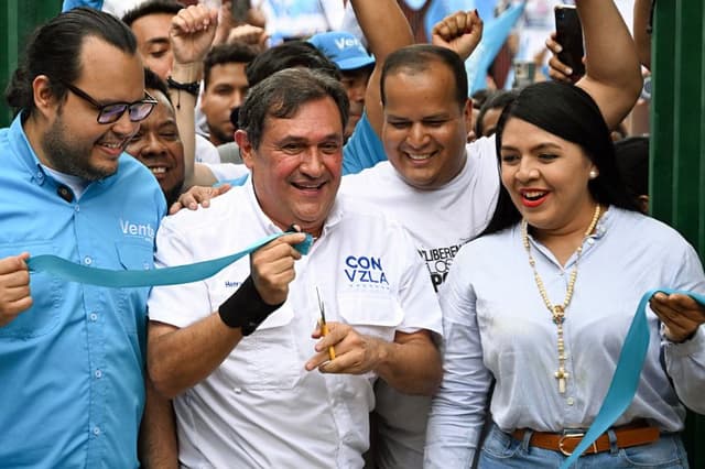 El coordinador nacional del partido político VENTE Venezuela, Henry Álvarez (C), sonríe tras cortar la cinta de la sede del partido, que abrió sus puertas por primera vez en 20 meses, en Caracas, el 28 de marzo de 2026. (Juan BARRETO/AFP vía Getty Images)