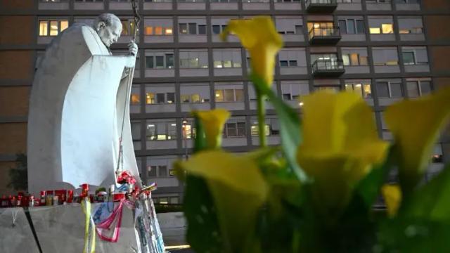 Se depositan flores ante la estatua de Juan Pablo II en el exterior del Hospital Universitario Gemelli, donde el Papa Francisco está hospitalizado por neumonía, en Roma, el 7 de marzo de 2025. (Alberto Pizzoli/AFP vía Getty Images)