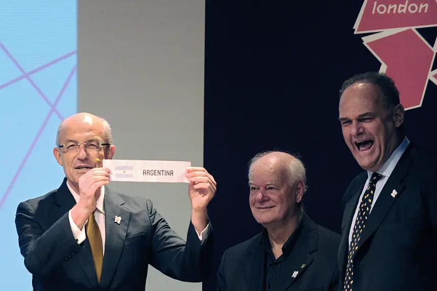 El exjugador de baloncesto brasileño Oscar Schmidt (d) hace un gesto mientras el director deportivo de la Federación Internacional de Baloncesto (FIBA) y exjugador de baloncesto Lubomir Kotleba (i) muestra el papel de Argentina para el grupo A, junto al exjugador brasileño Wlamir Marques (c), durante el sorteo de los grupos de baloncesto masculino para los Juegos Olímpicos de Londres 2012 en la sede de la Confederación Olímpica Brasileña (COB) en Río de Janeiro, Brasil, el 30 de abril de 2012. (Vanderleialmeida/AFP/GettyImages)