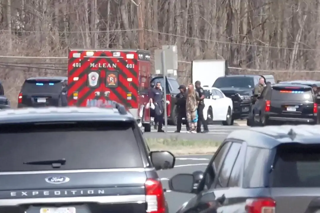 Oficiales escoltan a un hombre esposado hacia una ambulancia frente a la sede de la CIA en Langley, Virginia, el 19 de marzo de 2025. (Reuters/Captura de pantalla vía The Epoch Times)