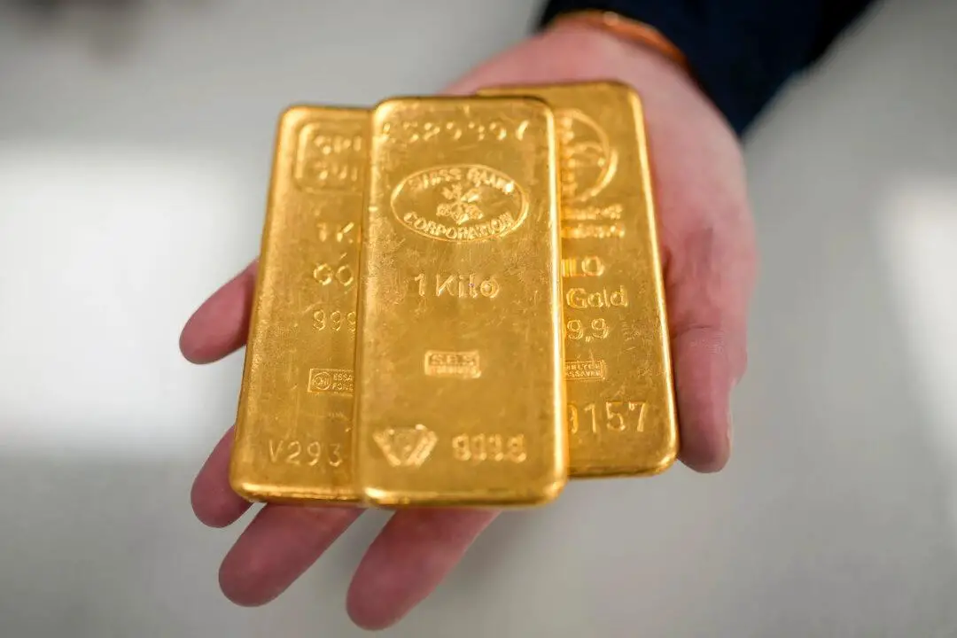 Un comerciante de oro posa con tres lingotes de oro de 1 kg en Birmingham, Inglaterra, el 13 de diciembre de 2023. (Christopher Furlong/Getty Images)