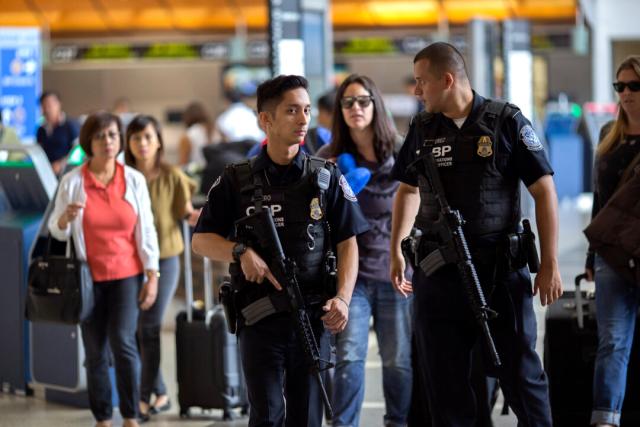 Oficiales de Aduanas y Protección Fronteriza de EE. UU. vigilan a los viajeros en el Aeropuerto Internacional de Los Ángeles, en Los Ángeles, el 2 de julio de 2016. (David McNew/Getty Images)