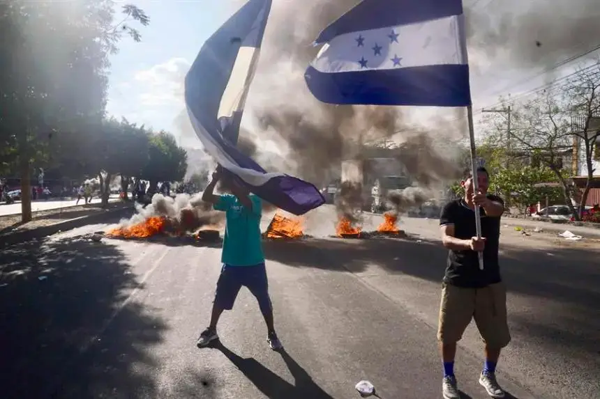 Foto de archivo de simpatizantes del Partido Nacional de Honduras ondeando banderas y quemando llantas en una calle, con la exigencia que llegaran urnas de votación a su barrio en Tegucigalpa (Honduras). EFE/ STR