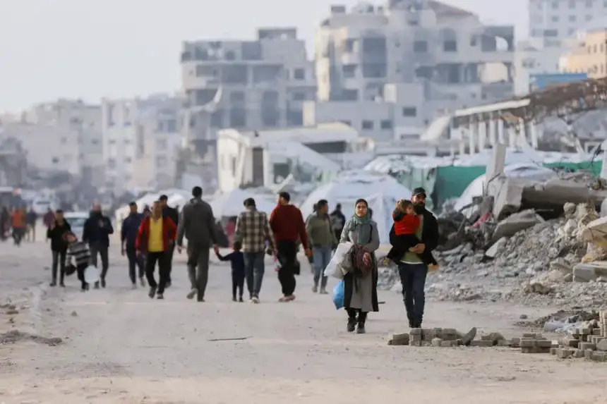 La gente se mueve por un sendero de arena cerca de edificios derrumbados en la ciudad de Gaza el 25 de marzo de 2025. Miles de personas se han visto obligadas a reubicarse después de las órdenes de evacuación de los residentes de Beit Lahia y Beit Hanoun. (Saeed Jaras/Middle East Images/AFP vía Getty Images)