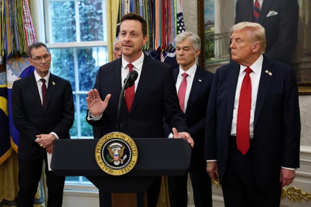 El director de Medicare y subadministrador de los Centros de Servicios de Medicare y Medicaid (CMS), Chris Klomp (centro), toma la palabra mientras (de izquierda a derecha) el director ejecutivo de Pfizer, Albert Bourla; el administrador de los Centros de Servicios de Medicare y Medicaid, Mehmet Oz, y el presidente de Estados Unidos, Donald Trump, observan tras el anuncio de Trump de un acuerdo con Pfizer para reducir los precios de los medicamentos de Medicaid en el Despacho Oval de la Casa Blanca, el 30 de septiembre de 2025 en Washington, D.C. (Win McNamee/Getty Images).