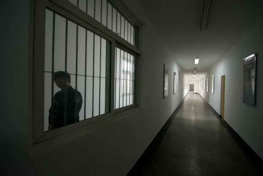 Un guardia mira a través de la ventana de un pasillo dentro de un centro de detención. (Ed Jones/AFP vía Getty Images).