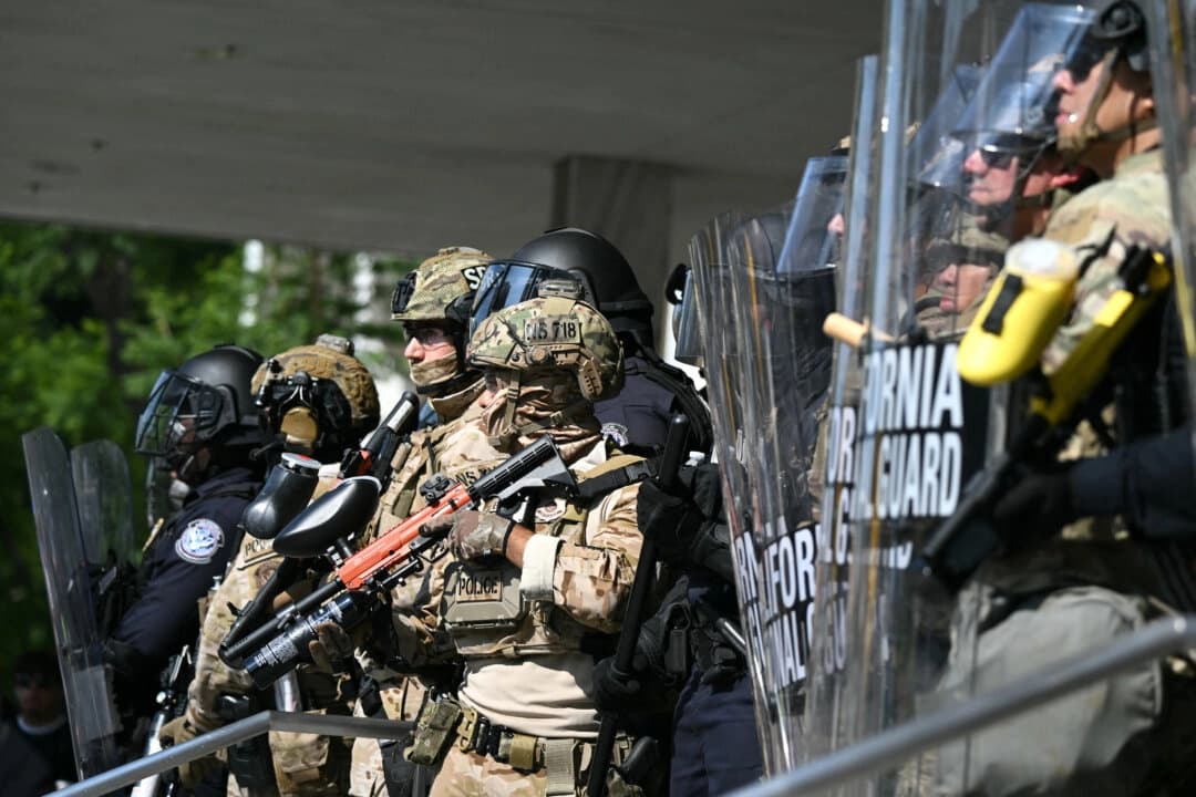Agentes de policía rodeados por miembros de la Guardia Nacional de California frente al edificio federal durante una protesta en respuesta a las operaciones federales de inmigración en Los Ángeles, el 9 de junio de 2025. (Ronaldo Schemidt/AFP a través de Getty Images)
