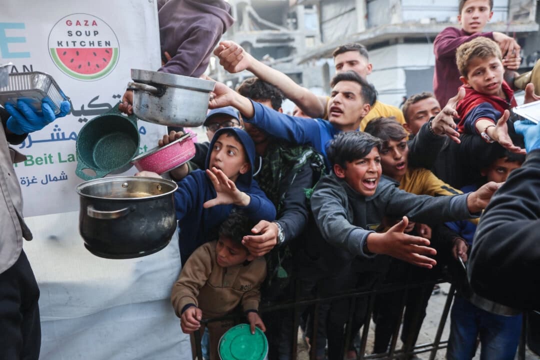 Niños palestinos desplazados se agolpan en una cola para recibir una ración de comida preparada en un comedor social en Beit Lahia, en el norte de la Franja de Gaza, el 9 de marzo de 2025. (Omar al-Qattaa/ AFP vía Getty Images)