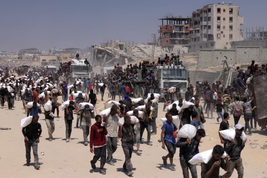 La gente camina con sacos de harina entregados tras la entrada de camiones con ayuda humanitaria en el norte de Gaza, procedentes del paso fronterizo de Zikim, el 27 de julio de 2025. (Bashar Taleb/AFP a través de Getty Images).