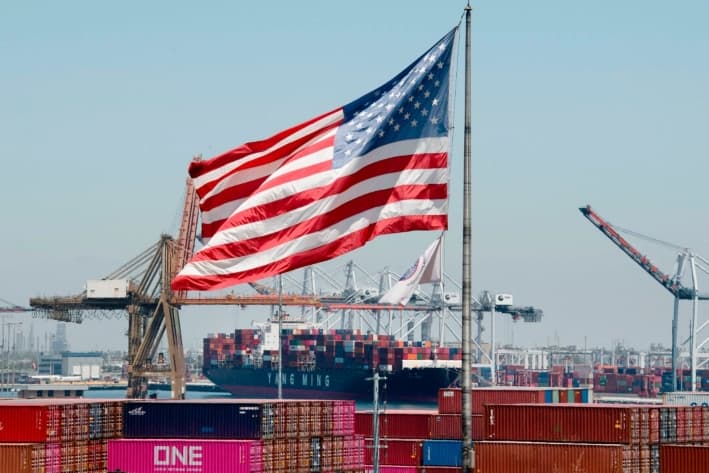 La bandera estadounidense ondea sobre un buque portacontenedores que deja su carga procedente de Asia, en el puerto de Long Beach, California, el 1 de agosto de 2019. (Mark Ralston/AFP vía Getty Images)
