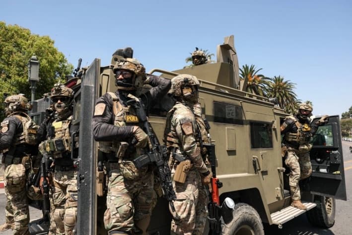 Agentes federales de la Oficina de Aduanas y Protección Fronteriza (CBP) viajan en un vehículo blindado que circula lentamente por Wilshire Boulevard, cerca del Parque MacArthur, en Los Ángeles, California, el 7 de julio de 2025. (Patrick T. Fallon/AFP vía Getty Images)