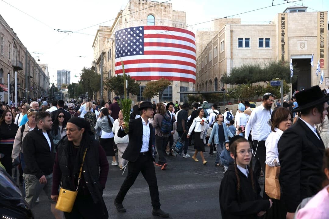 Israelíes pasan junto a una bandera estadounidense en el centro de Jerusalén antes de la llegada del presidente de los Estados Unidos, Donald Trump, el 12 de octubre de 2025. (Ahmad Gharabli/AFP a través de Getty Images)