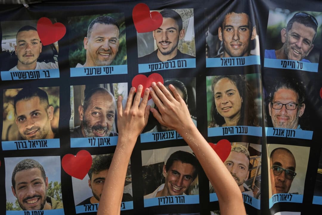 Una persona pega una estampa con forma de corazón en una pancarta con fotos de rehenes israelíes durante una concentración en una plaza conocida como Plaza de los Rehenes en Tel Aviv, Israel, el 13 de octubre de 2025. (Oded Balilty/AP Photo)