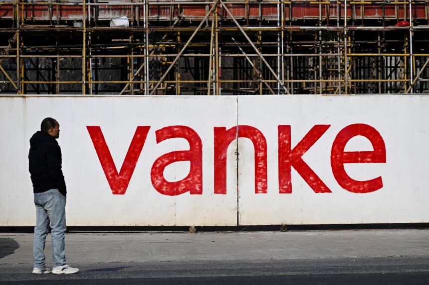 Un hombre se encuentra frente a la obra de un complejo residencial que está construyendo la promotora inmobiliaria china Vanke en Nanjing, provincia de Jiangsu (China), el 13 de febrero de 2025. (AFP vía Getty Images).