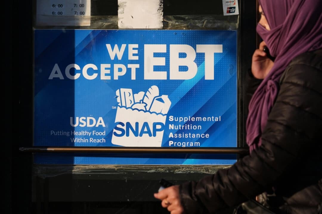 Un cartel informativo sobre el programa SNAP EBT se exhibe en una panadería mientras una mujer pasa por delante en Chicago el 2 de noviembre de 2025. (Nam Y. Huh/Foto de AP)