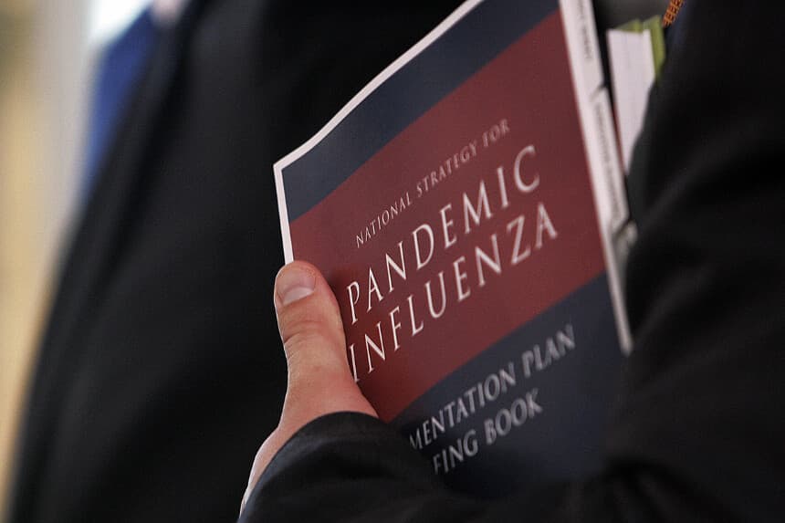 Un periodista sostiene el informe del Gobierno de EE. UU. sobre la Estrategia Nacional para la Gripe Pandémica durante una rueda de prensa en la Casa Blanca, en Washington D. C., el 3 de mayo de 2006. (JIM WATSON/AFP a través de Getty Images)