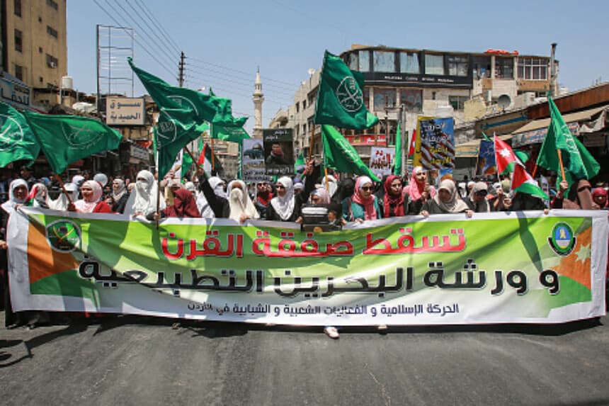 Mujeres marchan con banderas de la Hermandad Musulmana detrás de una gran pancarta en la que se lee en árabe "Abajo el acuerdo del siglo y el taller de normalización de Baréin", durante una manifestación. (KHALIL MAZRAAWI/AFP via Getty Images).
