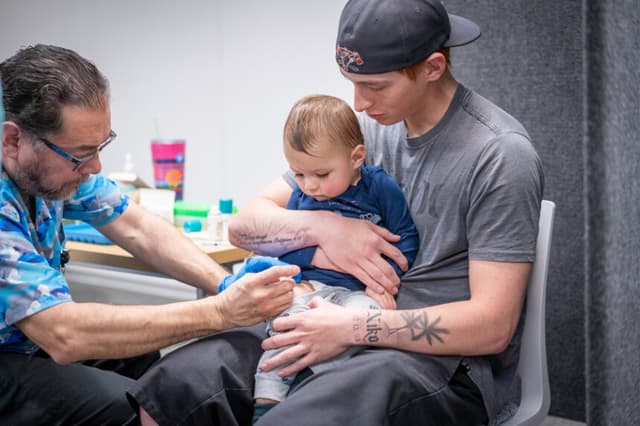 Ethan Turner sostiene a su hijo de 14 meses, Niko, mientras Raynard Covarrubio le administra la vacuna triple vírica en una clínica de vacunación organizada por el Departamento de Salud Pública de Lubbock el 1 de marzo de 2025 en Lubbock, Texas. (Foto de Jan Sonnenmair/Getty Images)