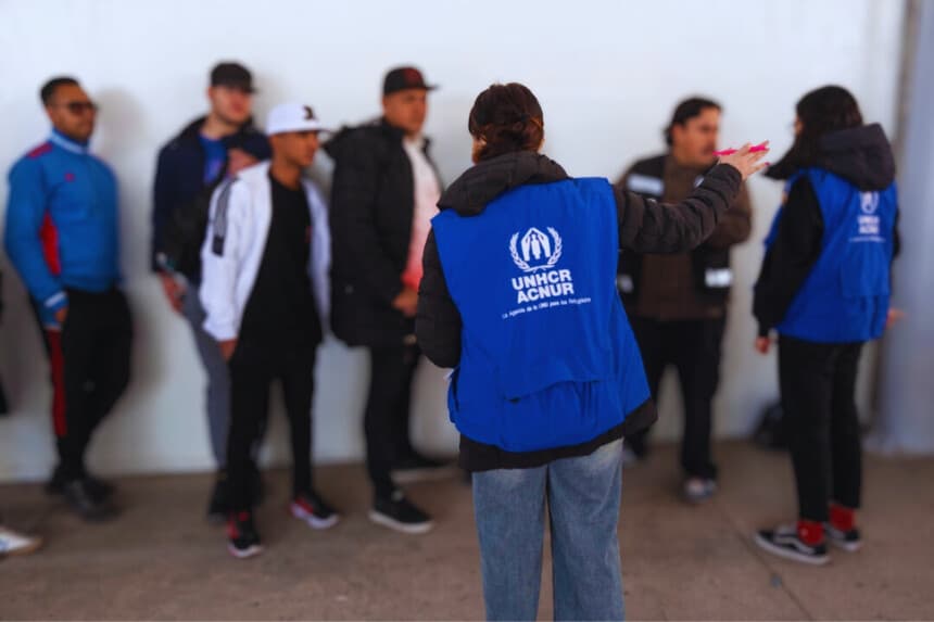 Solicitantes de asilo escuchan a los trabajadores del ACNUR en la entrada de la Comisión Mexicana de Ayuda a Refugiados y las oficinas del ACNUR en Tijuana, estado de Baja California, México, el 24 de enero de 2025. (Guillermo Arias/AFP a través de Getty Images)
