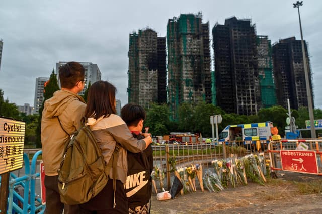 Las personas depositan flores frente al Wang Fuk Court tras el mortal incendio ocurrido en el distrito Tai Po de Hong Kong, el 30 de noviembre de 2025. (Anthony Kwan/Getty Images)