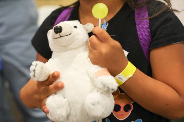 Una niña sostiene un osito de peluche con una tirita después de recibir una vacuna contra la gripe durante una campaña de vacunación en el Centro de Recursos Comunitarios L.A. Care y Blue Shield of California Promise Health Plan, en el barrio Panorama City de Los Ángeles, California, el 24 de octubre de 2025. (Foto de PATRICK T. FALLON/AFP vía Getty Images)