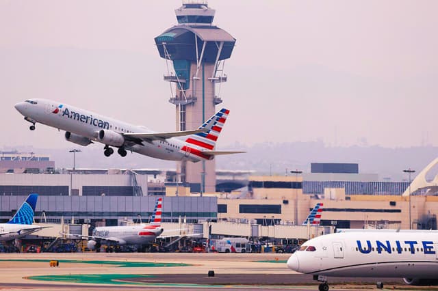 Un avión de American Airlines despega cerca de la torre de control del tráfico aéreo del Aeropuerto Internacional de Los Ángeles (LAX) el 12 de noviembre de 2025 en Los Ángeles, California. (Mario Tama/Getty Images)