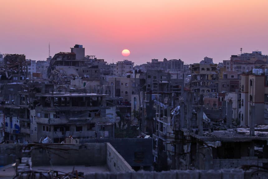El sol se pone detrás de edificios residenciales gravemente dañados en Jabalia, en el norte de la Franja de Gaza, el 17 de febrero de 2025, mientras la gente regresa al norte de Gaza durante el actual acuerdo de alto el fuego en la guerra entre Israel y Hamás. El primer ministro israelí, Benjamin Netanyahu, dijo el 17 de febrero que estaba "comprometido" con el plan del presidente estadounidense Donald Trump para Gaza, que implica el desplazamiento de más de dos millones de habitantes del territorio palestino. (Foto de BASHAR TALEB / AFP) (Foto de BASHAR TALEB/AFP a través de Getty Images).