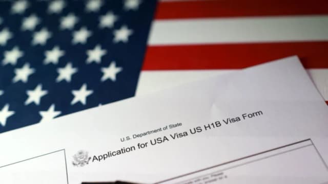 Una bandera estadounidense y un formulario de solicitud de visa H-1B, el 22 de septiembre de 2025. (Dado Ruvic/Ilustración/Reuters)
