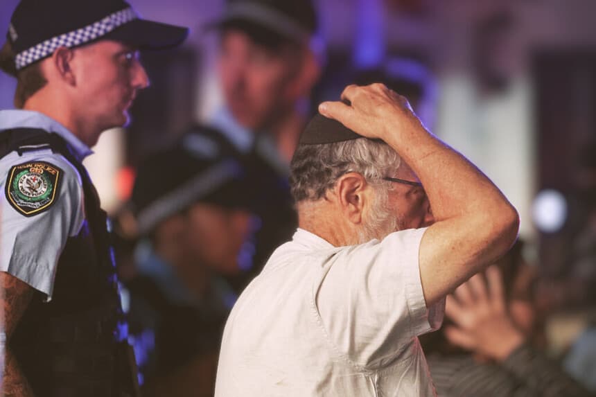 Un miembro de la comunidad judía reacciona mientras camina con la policía hacia el lugar del tiroteo en Bondi Beach, en Sídney, el 14 de diciembre de 2025. La policía australiana informó de que dos personas fueron detenidas tras recibir informes de múltiples disparos el 14 de diciembre en la famosa playa de Bondi Beach, en Sídney, e instó a la población a ponerse a cubierto. (DAVID GRAY / AFP a través de Getty Images)