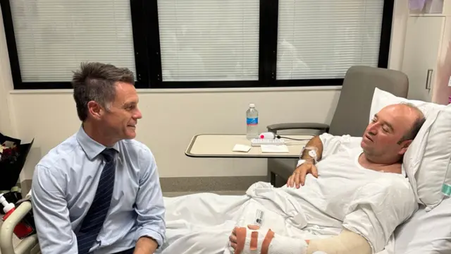 Fotografía publicada en el perfil de X del líder político de Nueva Gales del Sur, Chris Minns, que muestra a Minns (i) visitando en el hospital a Ahmed al Ahmed, el hombre que desarmó a uno de los autores del atentado perpetrado ayer en Sídney. Junto a la fotografía, Minns define a Ahmed como "un héroe de verdad" cuya "increíble valentía sin duda salvó innumerables vidas al desarmar a un terrorista con un enorme riesgo personal". Ahmed, de 43 años, se escondió el domingo detrás de unos vehículos para sorprender a uno de los asaltantes y forcejear con él hasta quitarle con sus propias manos el rifle con el que disparaba a los transeúntes en la popular playa de Bondi. Como consecuencia, Ahmed recibió disparos en el brazo y la mano. (EFE/ Chris Minns vía red social X)