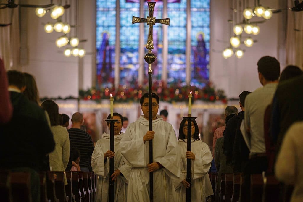 Monaguillos caminan por el pasillo con velas y una cruz después de un servicio de Christingle, en la catedral de San Pablo de Hong Kong durante la Nochebuena del 24 de diciembre de 2016. / AFP / TENGKU Bahar (TENGKU BAHAR/AFP a través de Getty Images)