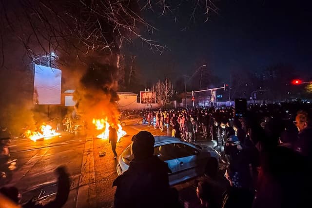 Iraníes se reúnen mientras bloquean una calle durante una protesta en Teherán, Irán, el 9 de enero de 2026. Las protestas a nivel nacional comenzaron en el Gran Bazar de Teherán contra las políticas económicas fallidas a finales de diciembre, se extendieron a las universidades y otras ciudades, e incluyeron consignas económicas, políticas y antigubernamentales. (MAHSA/Middle East Images/AFP vía Getty Images)