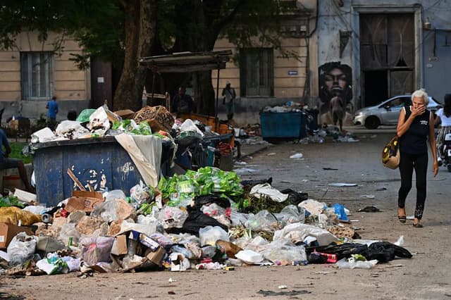 Una mujer se tapa la nariz al pasar junto a la basura en una calle de La Habana el 4 de diciembre de 2025. (YAMIL LAGE/AFP a través de Getty Images)