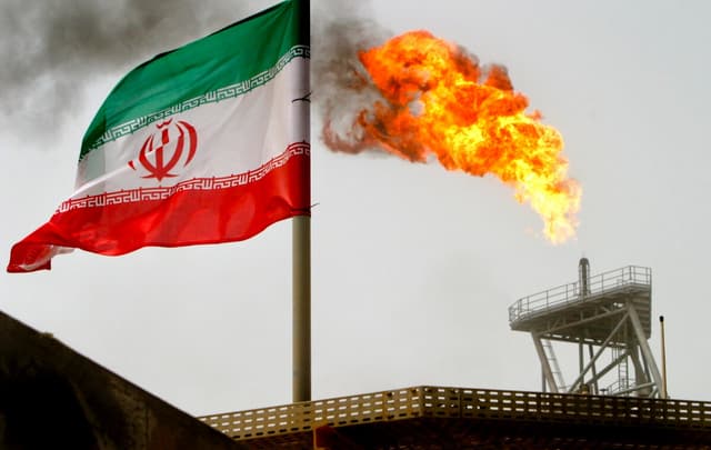 Una antorcha de gas en una plataforma petrolífera junto a una bandera iraní en el Golfo Pérsico, el 25 de julio de 2005. (Raheb Homavandi/Reuters).