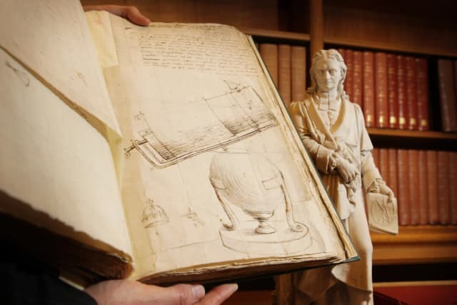 Un dibujo de Isaac Newton de su telescopio, incluido en un libro de sus cartas, se exhibe junto a su estatua en la Royal Society el 24 de noviembre de 2009 en Londres. (Peter Macdiarmid/Getty Images)