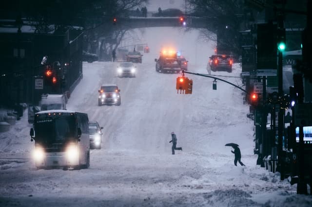 NUEVA YORK, NUEVA YORK - 25 DE ENERO: La gente cruza la calle mientras el tráfico circula durante una tormenta de nieve el 25 de enero de 2026 en la ciudad de Nueva York. Una enorme tormenta invernal está trayendo temperaturas gélidas, hielo y nieve a casi 200 millones de estadounidenses. (Foto de Andres Kudacki/Getty Images).