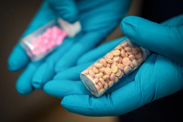 Jonathan Dumke, químico forense senior de la Administración para el Control de Drogas, sostiene viales de pastillas de fentanilo en un laboratorio de investigación de la DEA en el norte de Virginia el 29 de abril de 2025. (Angela Weiss/AFP vía Getty Images, Mark Schiefelbein/AP Photo, archivo)