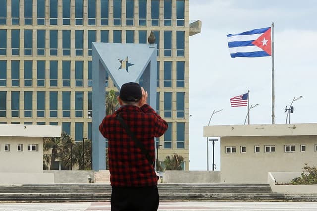 Un turista toma fotos de la embajada de Estados Unidos con la bandera estadounidense y la bandera cubana al fondo en La Habana, el 30 de enero de 2026.(ADALBERTO ROQUE / AFP a través de Getty Images)