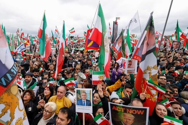 Los participantes enarbolan banderas, entre ellas la histórica bandera nacional iraní "León y Sol", así como carteles con la imagen del antiguo príncipe heredero de Irán y actual figura clave de la oposición, Reza Pahlavi, y del presidente estadounidense Donald Trump, durante una manifestación de la oposición iraní en el recinto ferial Theresienwiese, al margen de la 62.ª Conferencia de Seguridad de Múnich (MSC), celebrada en Múnich, Alemania, el 14 de febrero de 2026. (Michaela Stache/AFP a través de Getty Images)