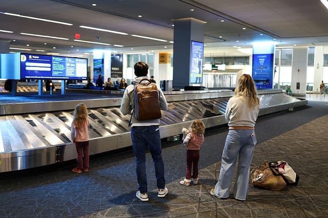 Una familia espera en la zona de recogida de equipajes del aeropuerto LaGuardia de Nueva York el 22 de febrero de 2026. (CHARLY TRIBALLEAU / AFP a través de Getty Images)