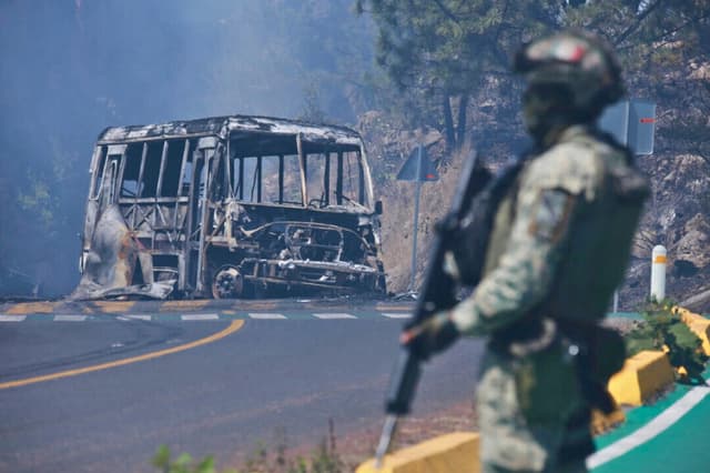 Un soldado monta guardia junto a un vehículo calcinado tras ser incendiado, en Cointzio, estado de Michoacán, México, el 22 de febrero de 2026, tras la muerte del líder del Cártel Jalisco Nueva Generación, Nemesio Oseguera, conocido como “El Mencho”. (Foto AP/Armando Solís).
