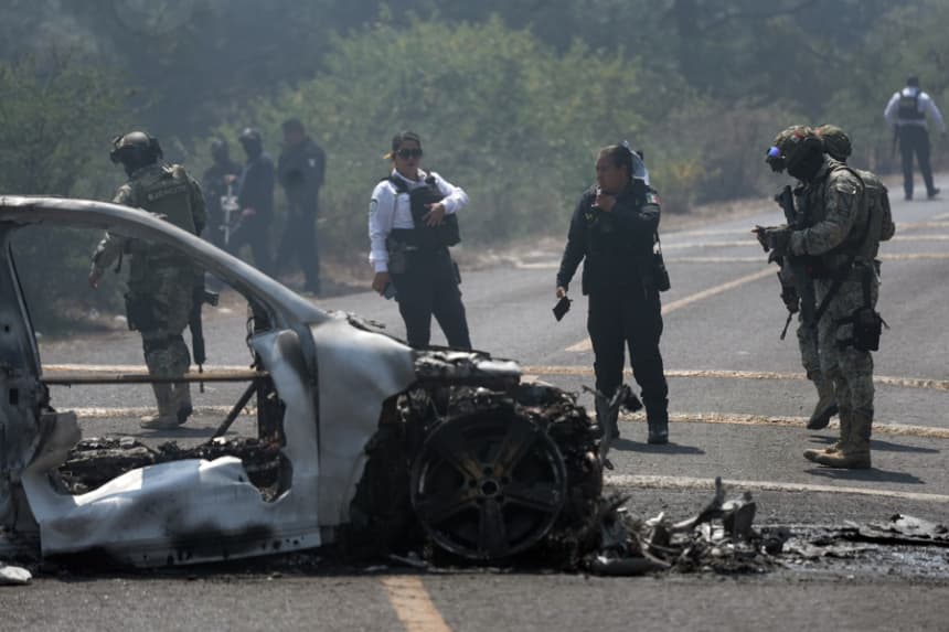 Integrantes de la policía de Morelia y del ejército trabajan en la zona donde fue incendiado un vehículo por presuntos integrantes del crimen organizado este domingo, tras el abatimiento de Nemesio Oseguera Cervantes, alias El Mencho, líder del Cártel Jalisco Nueva Generación (CJNG), en Morelia, México. (EFE/ Iván Villanueva)