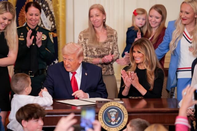 El presidente Donald Trump le da su bolígrafo a un niño después de firmar una proclamación para el Mes de la Historia de la Mujer con la primera dama Melania Trump durante un evento en la Sala Este de la Casa Blanca el 12 de marzo de 2026 en Washington. (Heather Diehl/Getty Images).