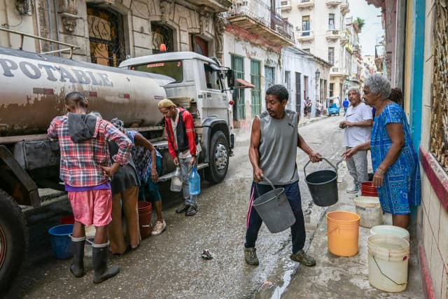 Varias personas esperan para llenar sus bidones y cubos desde un camión cisterna en La Habana, el 20 de marzo de 2026. Yamil Lage/AFP vía Getty Images