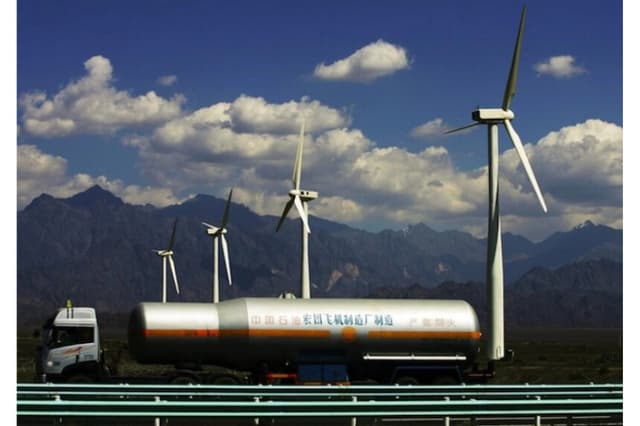Un camión petrolero pasa junto a turbinas eólicas en la planta de energía eólica de Dafancheng, la más grande de su tipo en Asia, en Dafancheng de la Región Autónoma Uygur de Xinjiang, China, en 2007. (Fotos de China/Getty Images)