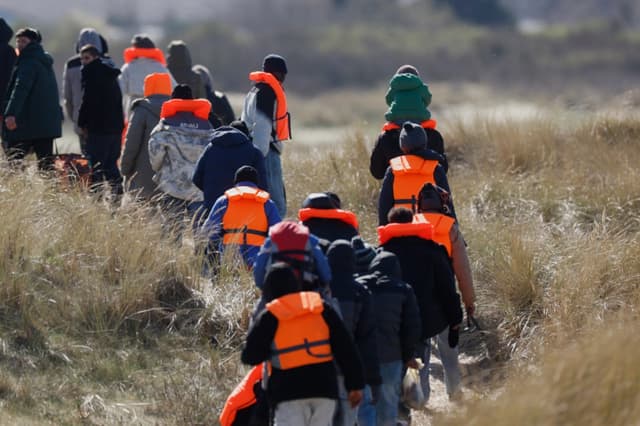 Migrantes que intentan llegar a Gran Bretaña caminan por la orilla de una playa en Gravelines, Francia, el 18 de marzo de 2026. (AP/Jean-Francois Badias)