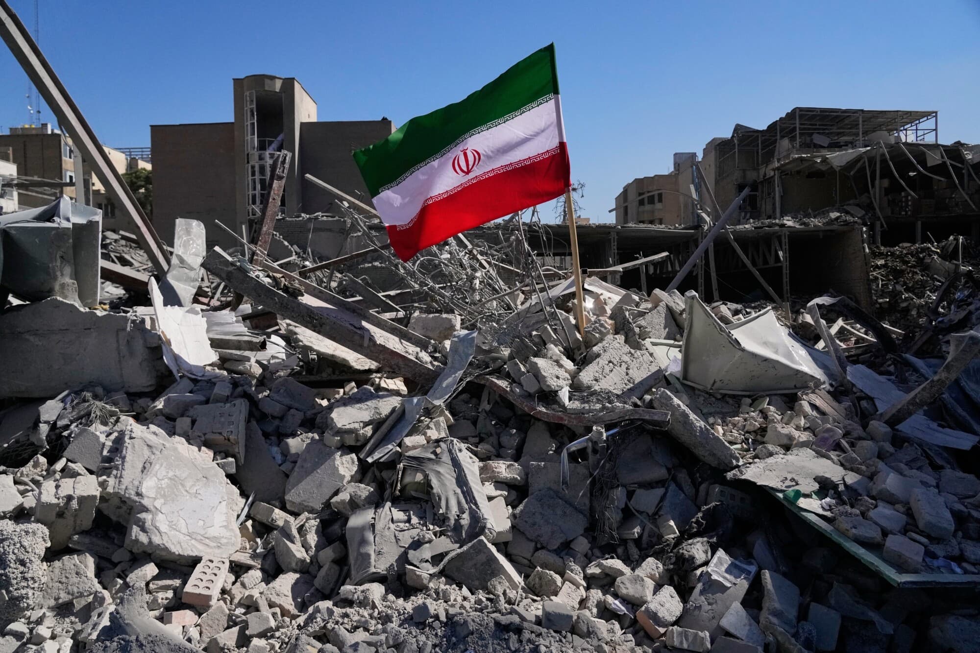 Una bandera iraní se encuentra entre las ruinas de una comisaría de policía alcanzada durante la campaña militar estadounidense-israelí en Teherán, Irán, el 3 de marzo de 2026. (Foto AP/Vahid Salemi)