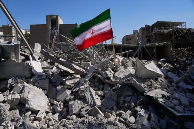 Una bandera iraní se encuentra entre las ruinas de una comisaría de policía alcanzada durante la campaña militar estadounidense-israelí en Teherán, Irán, el 3 de marzo de 2026. (Foto AP/Vahid Salemi)