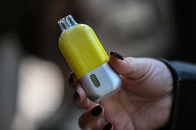Una joven sostiene un cigarrillo electrónico en diciembre de 2025. (Yuri CORTEZ / AFP vía Getty Images).