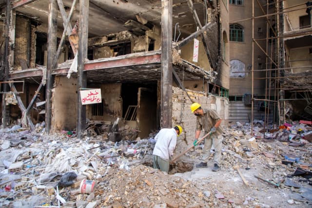 Varias personas trabajan en el lugar donde se encuentra un edificio residencial dañado que, según las autoridades iraníes, fue alcanzado por un ataque el 4 de marzo durante la campaña militar estadounidense-israelí en el sureste de Teherán, Irán, el 14 de abril de 2026. (Majid Saeedi/Getty Images)